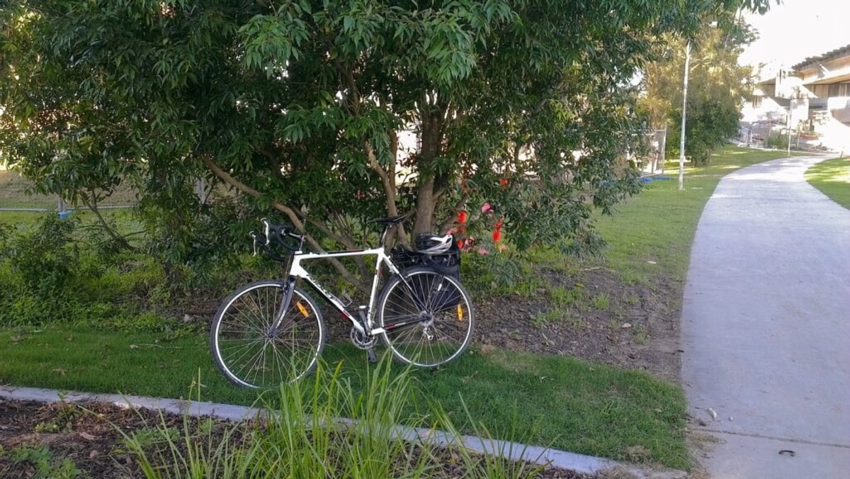 Black & white bike beside a bike path, complete with pannier and helmet.