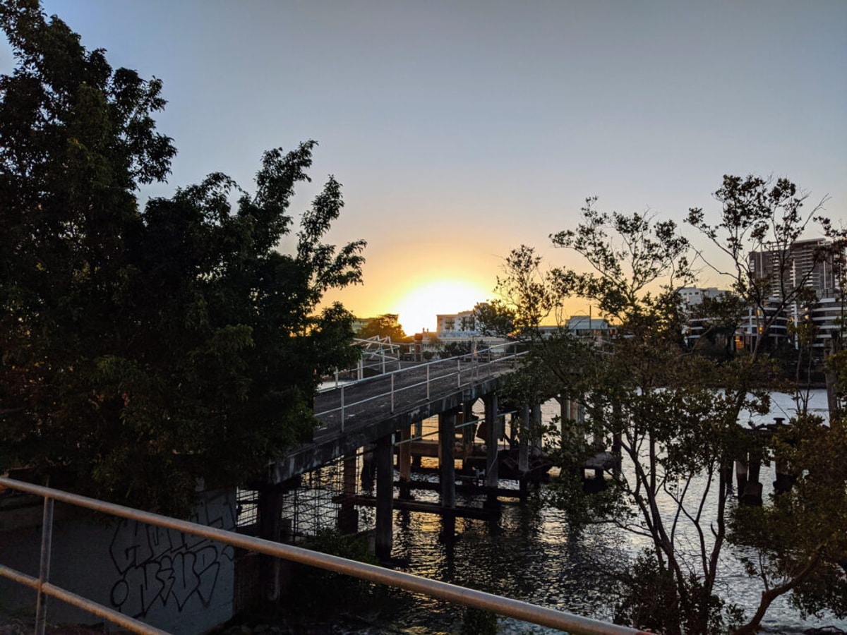 An old broken down pier that the party boat used to use before the 2011 floods. The sun is really low on the horizon, casting yellow rays everywhere.