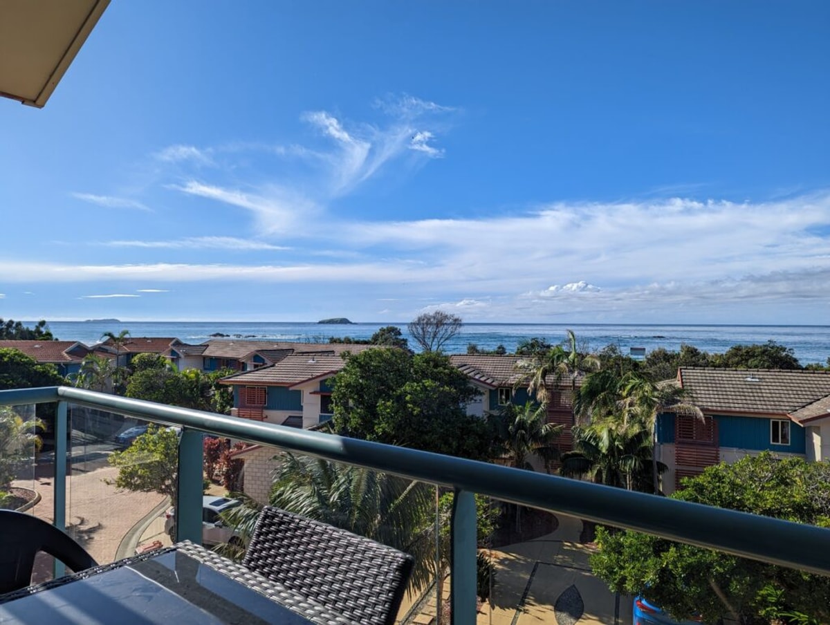 The view from the hotel balcony, there are some other holiday units, but we're up high and can see the ocean over the top of them. There are two islands jutting out of the water.