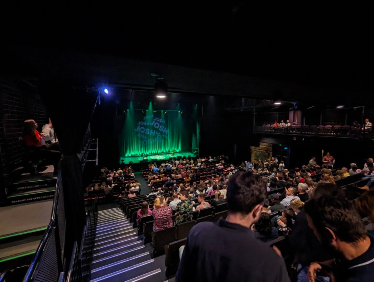 The Powerhouse from riiiiight up the back, the stage is lit green and has the words Josh repeated over and over. People are still taking their seats.
